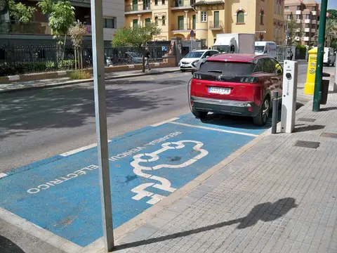 Coche eléctrico cargando en una plaza reservada de una calle de Málaga